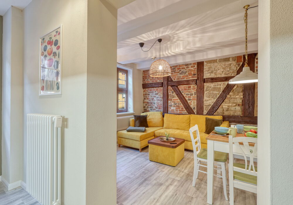 Wohnbereich mit senfgelben Sofa und Smart-TV Ferienwohnung Anna Quedlinburg